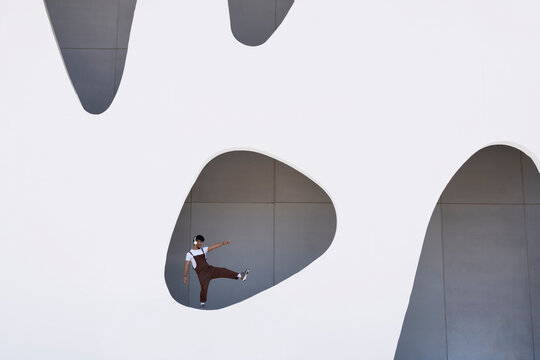 Young man playing on wall with hole in building