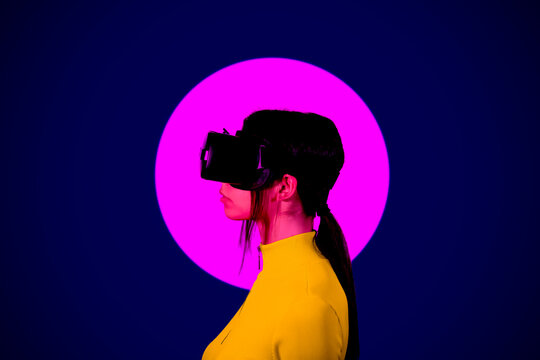 Young woman wearing VR Goggles by pink circle on black background