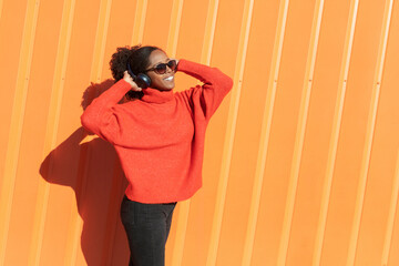 Happy woman wearing headphones listening to music on sunny day