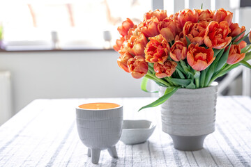 Spring composition with a bouquet of orange tulips in the interior of the house.