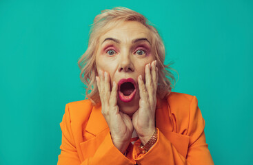 Shocked senior woman against turquoise background