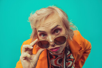 Woman adjusting sunglasses against colored background