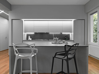 Close-up of a modern island kitchen with two stools in a white kitchen