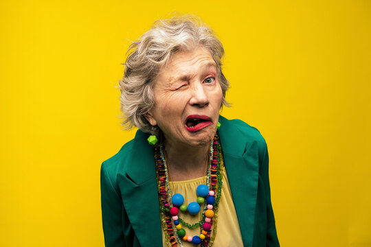 Senior woman making funny faces against yellow background