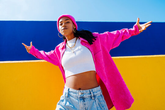 Woman with arms outstretched dancing in front of wall