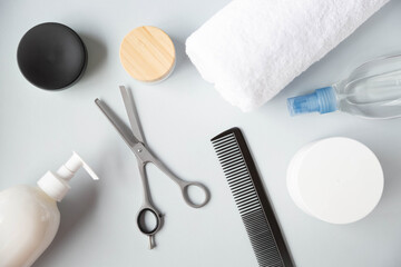 Naklejka premium Hairbrush, filleting scissor and other hairdressing salon accessories are on a grey background. View from the top point.