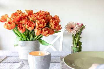 A bouquet of tulips and a candle on the table, close up.