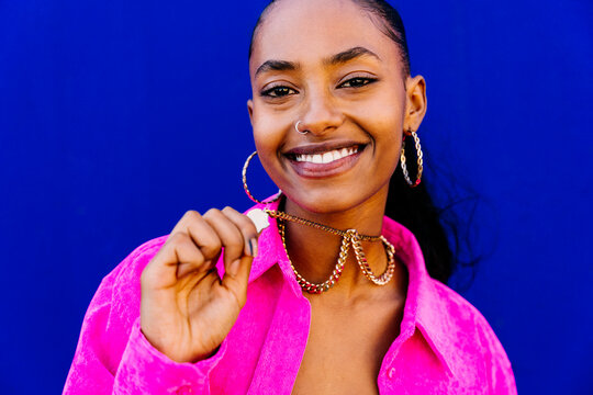 Young dancer wearing necklace in front of blue wall