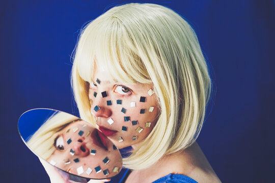 Reflection of blond woman seen on mirror against blue background