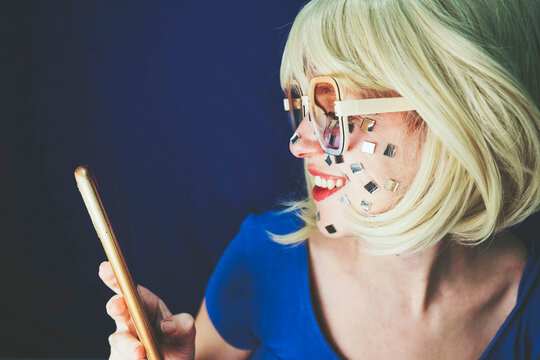 Smiling Blond Woman Using Smart Phone Against Blue Background