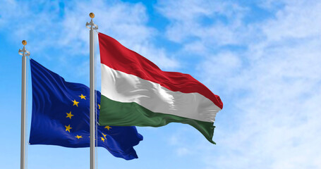 The flags of Hungary and the European Union fluttering together on a clear day