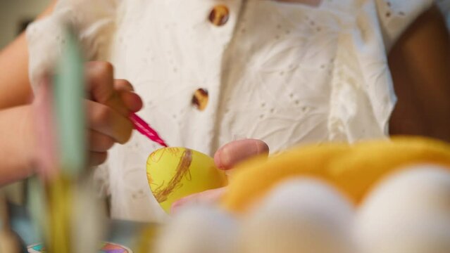 Easter holiday. Little girl cuts decorative Easter eggs with felt-tip pens while sitting at the table close-up. A little girl paints Easter eggs making decorations for the Easter holiday. 