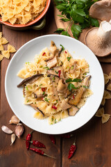 Piatto di deliziosa pasta piccante condita con funghi, aglio e prezzemolo, cibo italiano vegetariano 