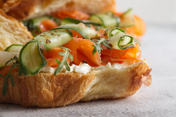 Croissants with cheese cream, red fish and cucumber close up 