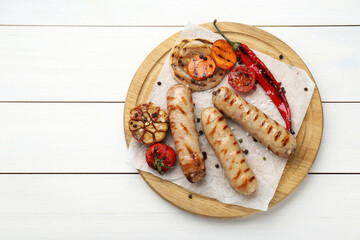 Tasty grilled sausages with vegetables on white wooden table, top view. Space for text
