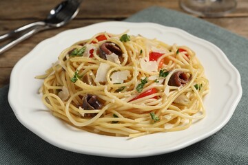 Delicious pasta with anchovies, tomatoes and parmesan cheese on table, closeup