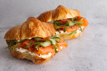 Croissants with cheese cream, red fish and cucumber close up 