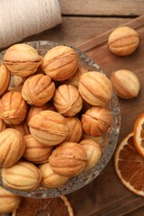 Bowl of delicious nut shaped cookies and dried orange slices on wooden table, flat lay