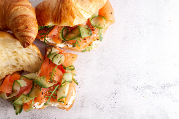 Croissants with cheese cream, red fish and cucumber close up with copy space