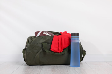 Gym bag and sports equipment on floor near white wall