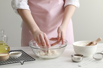 Woman making dough for traditional grissini at white wooden table indoors, closeup