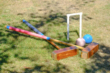 a hoop, 2 malletts and 2 balls from a game of Croquet in a garden - 576033793