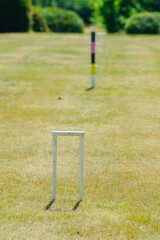 a post, hoop and hoops in t he distance from a game of Croquet in a garden - 576033920