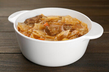 Tasty cabbage soup with meat and carrot on wooden table, closeup