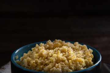 Wheat porridge in a ceramic bowl and a spoon on a wooden table. Homemade food.