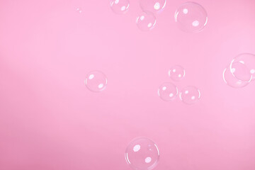 Many beautiful soap bubbles on pink background