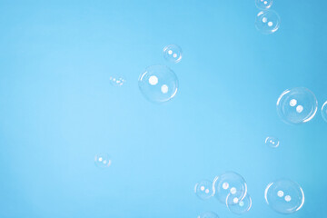 Many beautiful soap bubbles on light blue background. Space for text