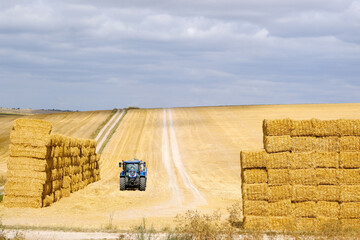 Two stacks of haybales with tractor in field - 576034789