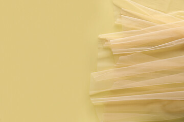 Beautiful tulle fabric on yellow background, top view. Space for text