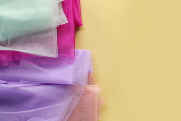 Beautiful tulle fabrics on yellow background, flat lay. Space for text