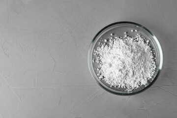 Petri dish with calcium carbonate powder on grey table, top view. Space for text