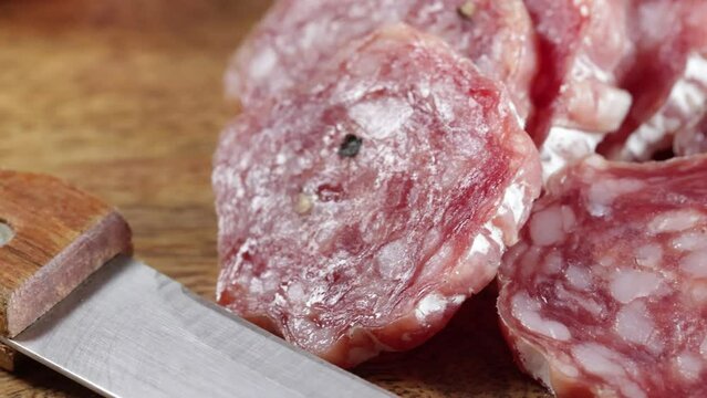 saucisson sec tranch&eacute; en gros plan sur une table en bois