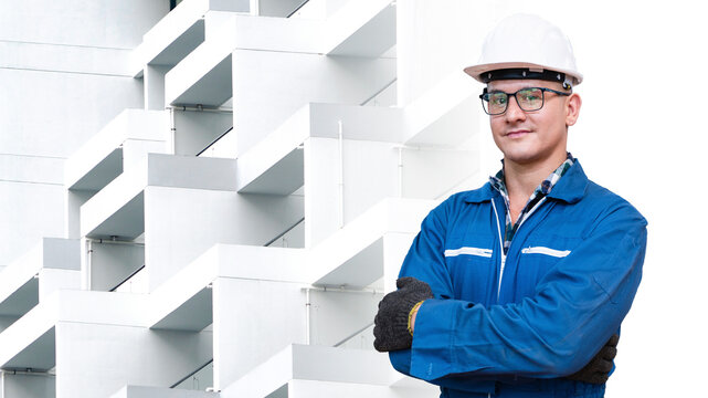 Portrait of manual man worker is standing with confident with blue working suite dress and safety helmet in front exterior white concrete pattern wall building background.