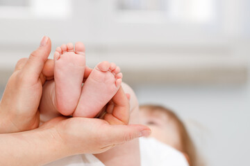 Close up of baby's foots in mother hands. Childhood and baby care concept