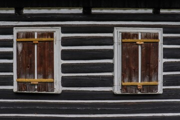 Wooden window shutter on traditional mountain cottage with brown and white facade