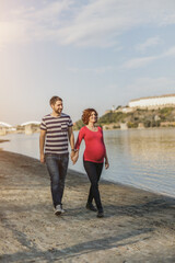 Expecting Couple Enjoying Walk Near The River