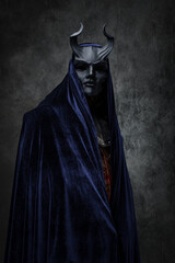 Naklejka premium Shot of ancient cult prayer dressed in horned mask and dark robe.