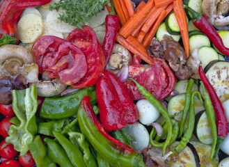 Variety of bright cut fresh vegetables. Green pepper, red pepper, mushroom, shiitake, potatoes, carrot, basil, chilli peppers, eggplant, garlic, zucchini, cut tomatoes, cherry, onion.