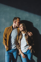 Happy couple in love dressed in shirts, standing on the background of gray wall, looking at empty space, isolated background of gray concrete wall. The concept of a happy couple in love.