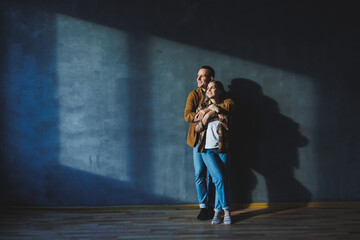 Happy couple in love dressed in shirts, standing on the background of gray wall, looking at empty space, isolated background of gray concrete wall. The concept of a happy couple in love.