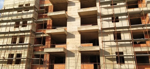Construction of a quarter of five-story houses made of monolithic concrete. Industry, construction, real estate. Building facade, scaffolding. New construction technologies for earthquake-prone areas