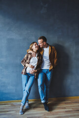 Happy couple in love dressed in shirts, standing on the background of gray wall, looking at empty space, isolated background of gray concrete wall. The concept of a happy couple in love.