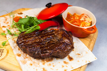 Pork steak with salad and pepper on the wooden chop board.