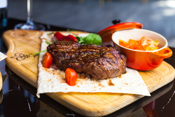 Pork steak with salad and pepper on the wooden chop board.