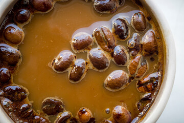 coffee beans in liquid coffee in a white mug