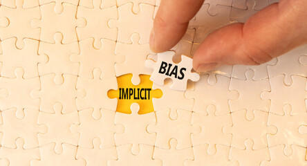 Implicit bias symbol. Concept words Implicit bias on white paper puzzles. Beautiful yellow table yellow background. Businessman hand. Business psychology implicit bias concept. Copy space.